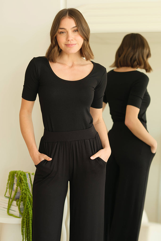 Model wearing a black fitted bamboo tee featuring a scoop neckline and above elbow sleeves.