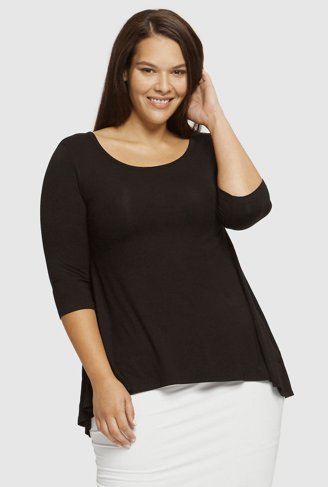 Woman wearing a black top and white skirt on a plain background