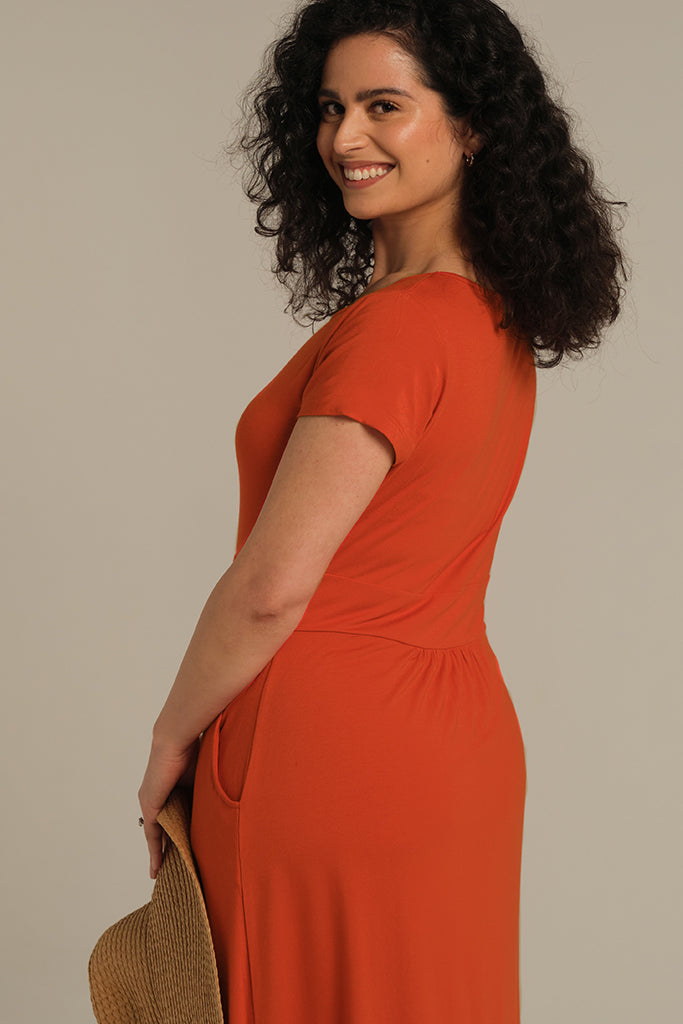 Closeup of model wearing a short sleeved dress in orange.