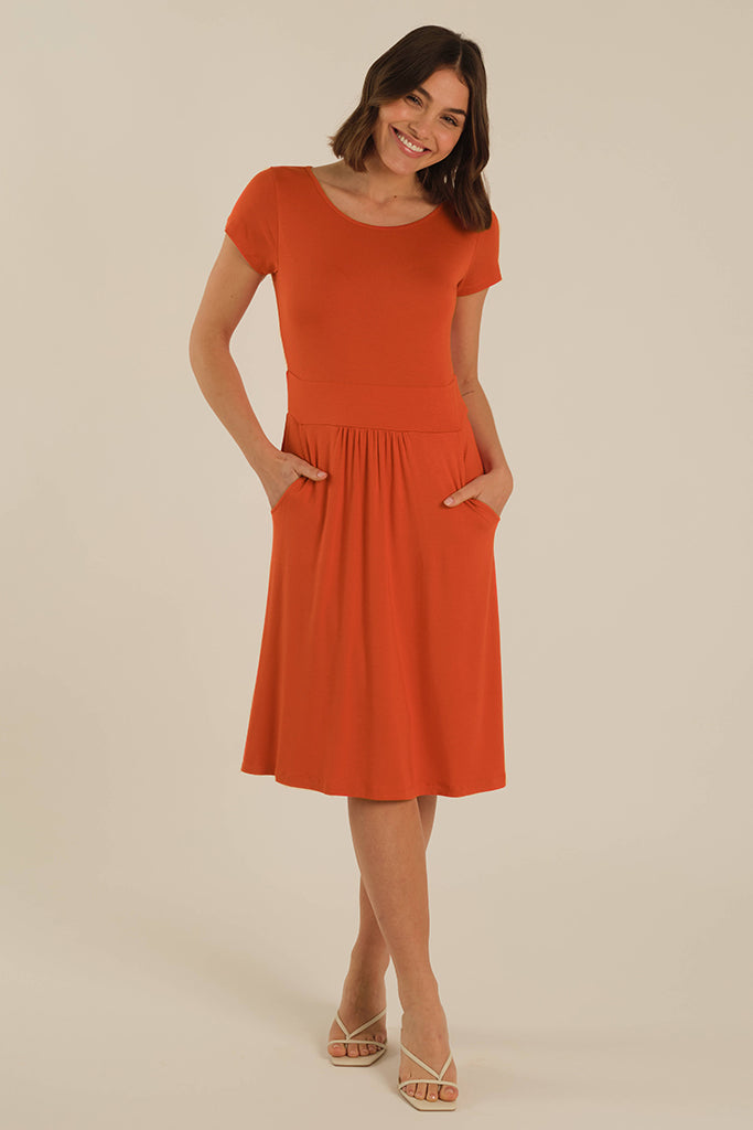 Model wearing a orange bamboo dress with her hands in the two side pockets