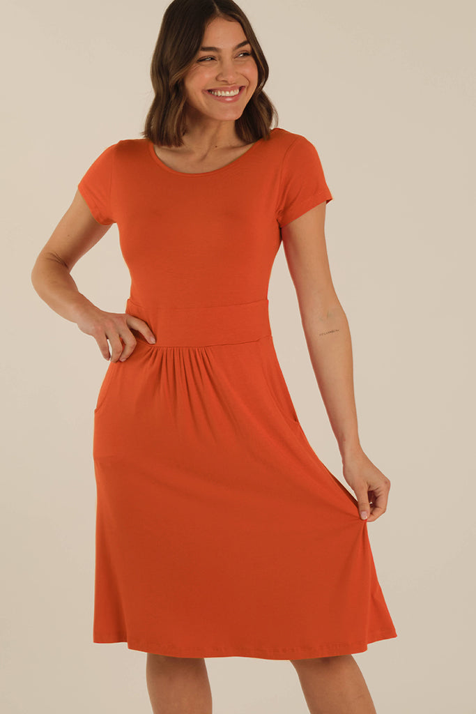 Closeup of model wearing a bright orange bamboo dress with a round neckline and relaxed fit.