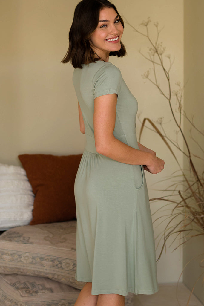 Side view of model smiling and wearing a sage green summer dress.