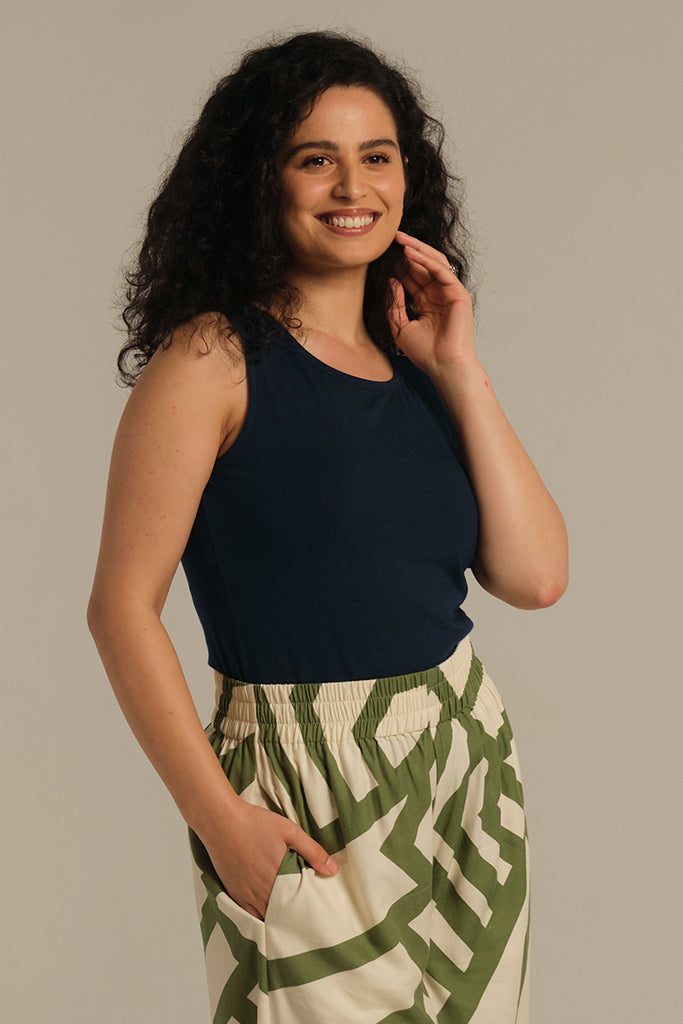 A woman wearing a dark navy sleeveless tank top with a high scoop neckline and thick shoulder straps.
