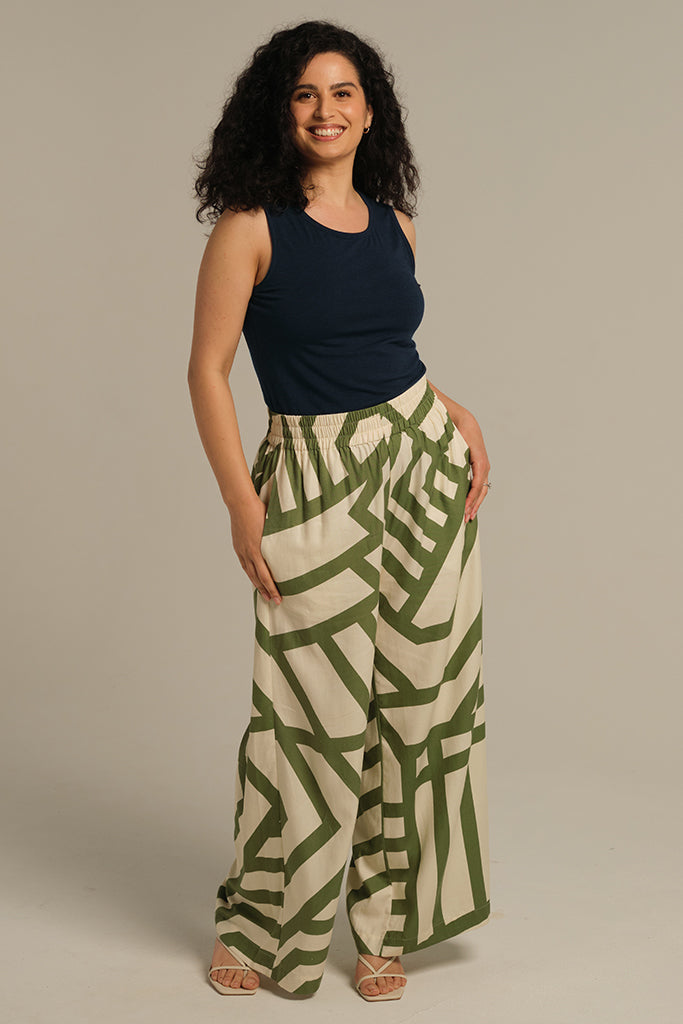 Model is wearing a dark navy high scoop neck singlet tucked into long wide leg pants.