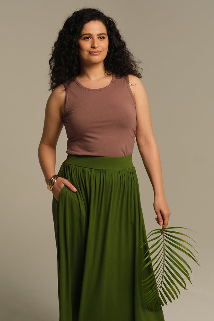 Brown fitted singlet with high scoop neckline tucked into green skirt.
