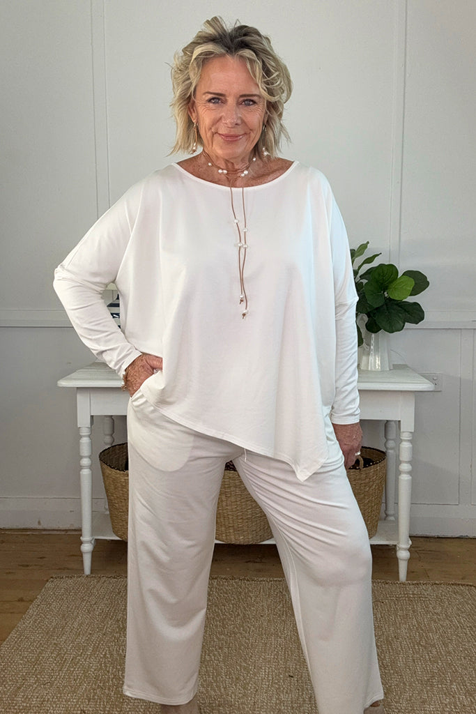 Woman wearing an outfit consisting of the voyager pant with a matching top in soft white