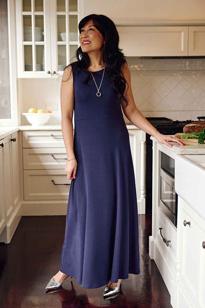 Woman in an indigo maxi dress standing in a kitchen.