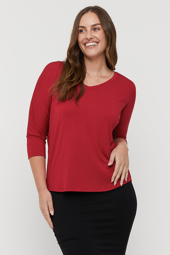 Model smiling wearing a red bamboo tee with dolman sleeves and a black tube skirt.