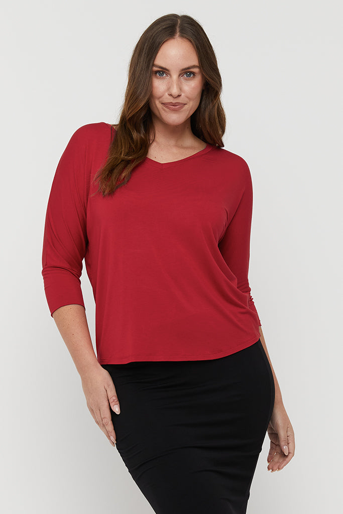 Model wearing a relaxed v neck tee in red made out of lightweight and breathable bamboo fabric.
