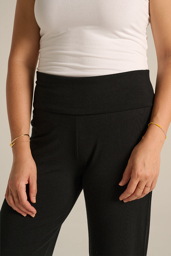 Detail of black pants showing smooth, wide fold-over waistband and flexible fit