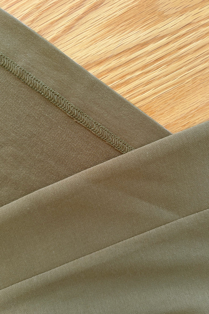 Close-up of green bamboo fabric with stitching detail on a wooden surface