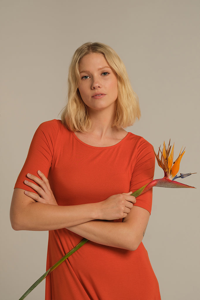Closeup of bamboo midi dress in orange, featuring scoop neckline and short sleeves.