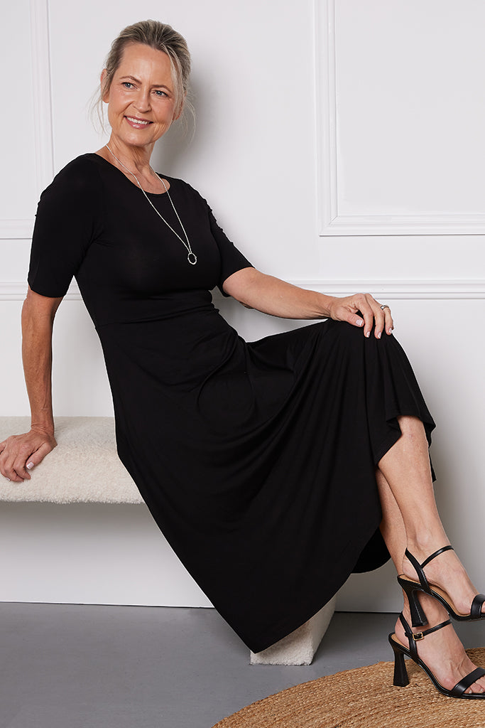 Model seated in black dress, showcasing comfortable bamboo fabric and flattering silhouette.