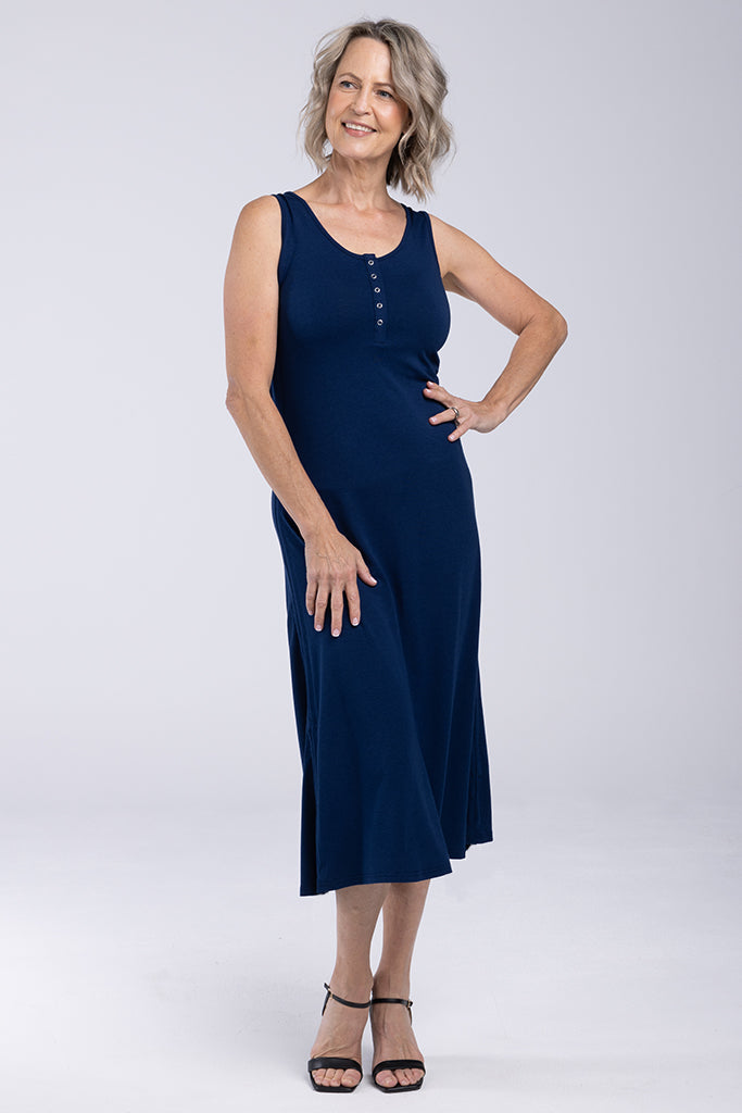A navy Henley tank dress with a henley neckline, sleeveless shoulders, and a midi length. The dress features small buttons and a draw cord on either side which can be ruched up or worn undone.