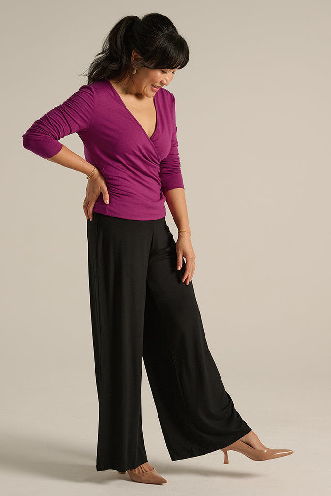 side view of the luxe wide leg pants in black paired with cross front top in berry
