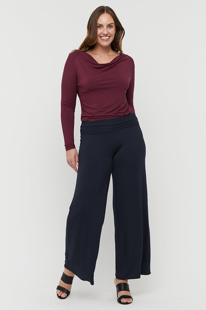 A woman wearing dark navy wide-leg pants and a maroon top with a round neckline.
