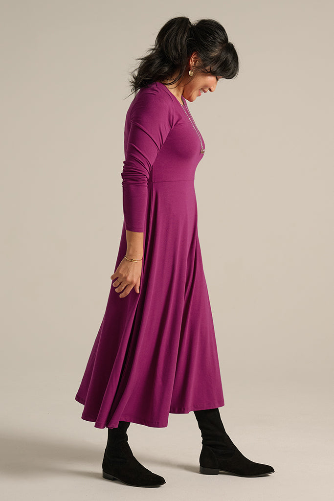 Long sleeve berry dress featuring a fitted bodice and flowing midi skirt.