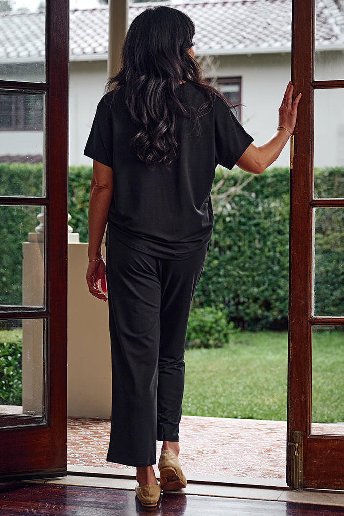 Back view of model wearing a short sleeved black tee and petite pants in bamboo french terry fabric.