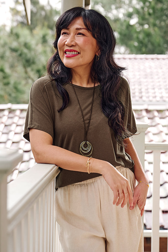Model wearing a brown tee featuring a high, round neckline and short sleeves