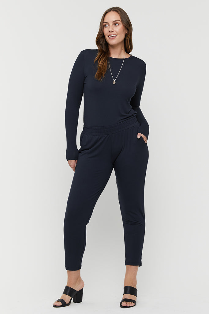 a woman wearing an outfit consisting of the dark navy Peggy trousers with a comfy elastic band and side pockets paired with the dark navy crew layering top with long sleeves