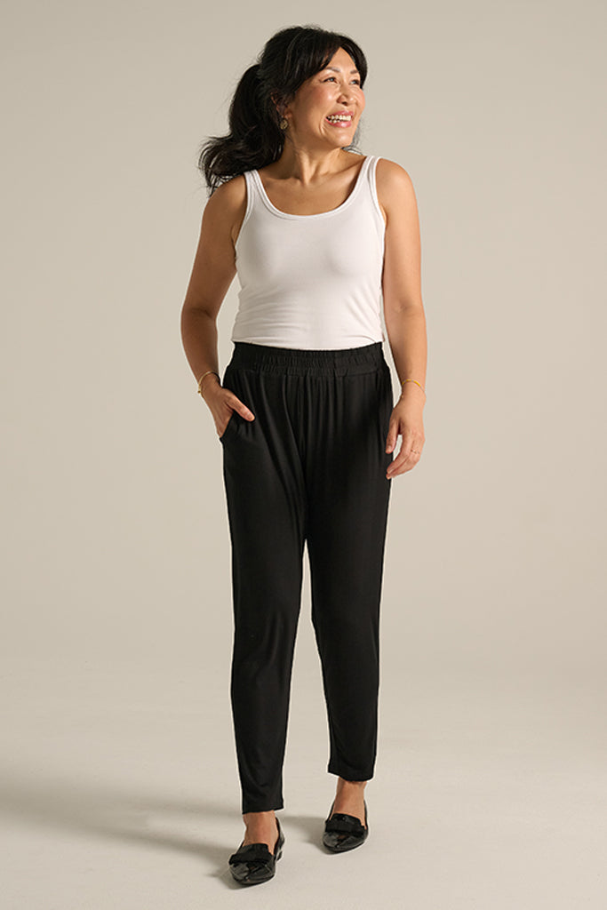 A woman wearing the Peggy Bamboo Trouser in black, featuring side pockets and a comfy elasticated band