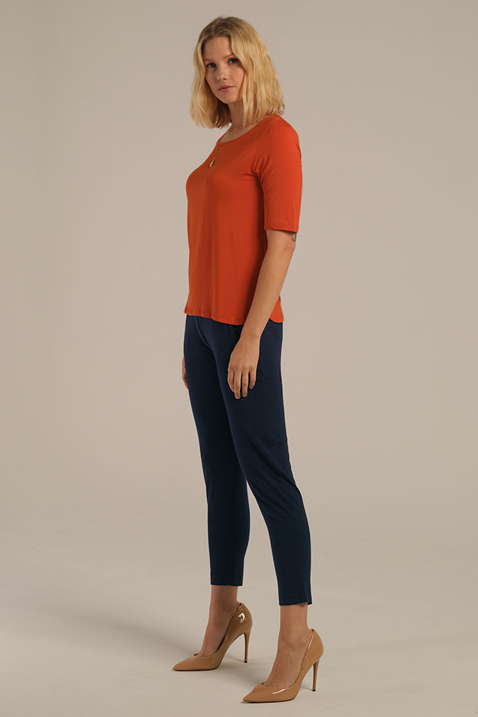 A woman wearing dark navy bamboo trouser pants with an elastic waistband and tapered leg