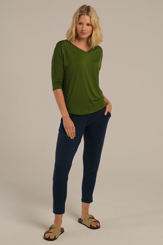 A woman wearing dark navy bamboo trouser pants with an elastic waistband and tapered leg.