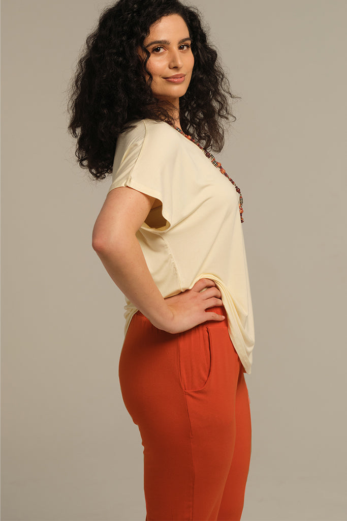 a side view of the peggy pants in orange with side pockets an a comfortable elastic band