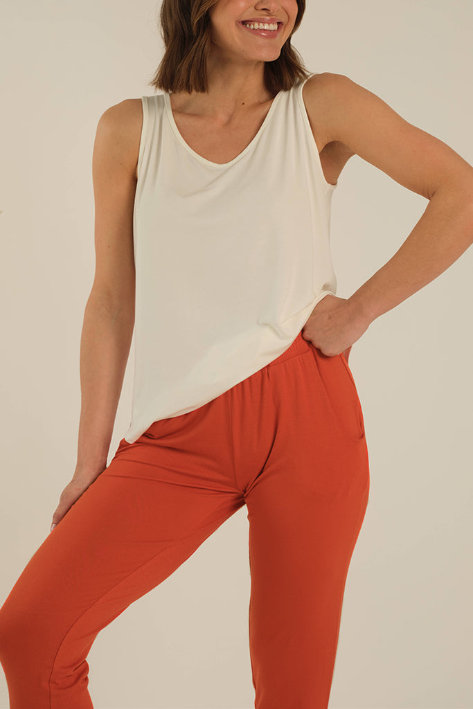 a detailed view of the Peggy bamboo pants featuring side pockets and an elastic waisband, pictured in the flame colour