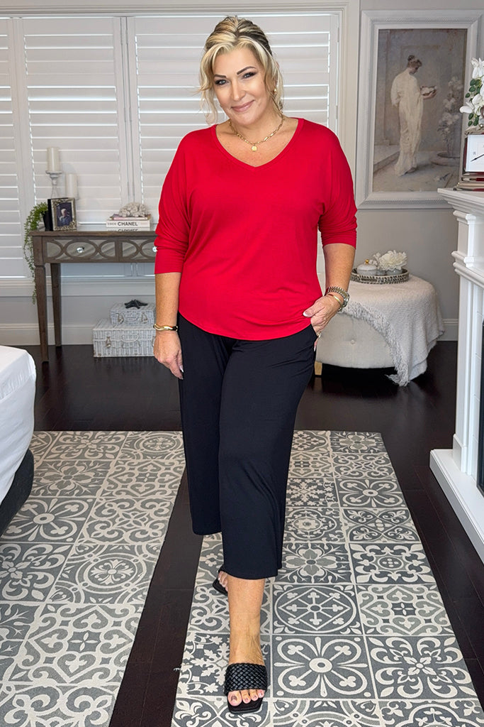 Curvy model wearing a red bamboo tee with a v neckline and dolman sleeves, paired with black bamboo pocket culottes