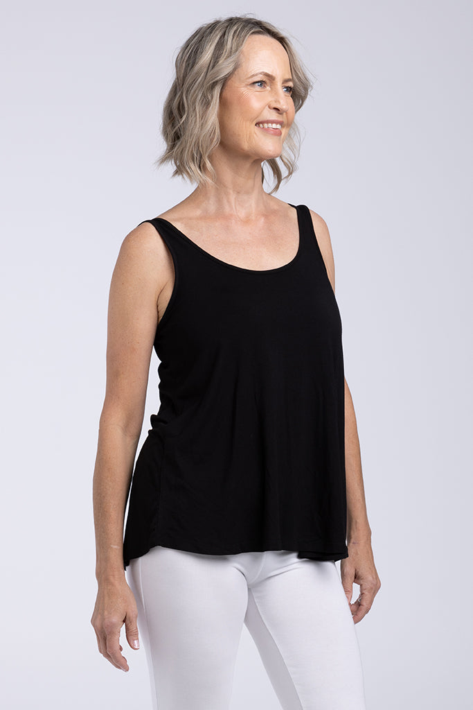 Woman standing wearing a black relaxed a line singlet with white pants