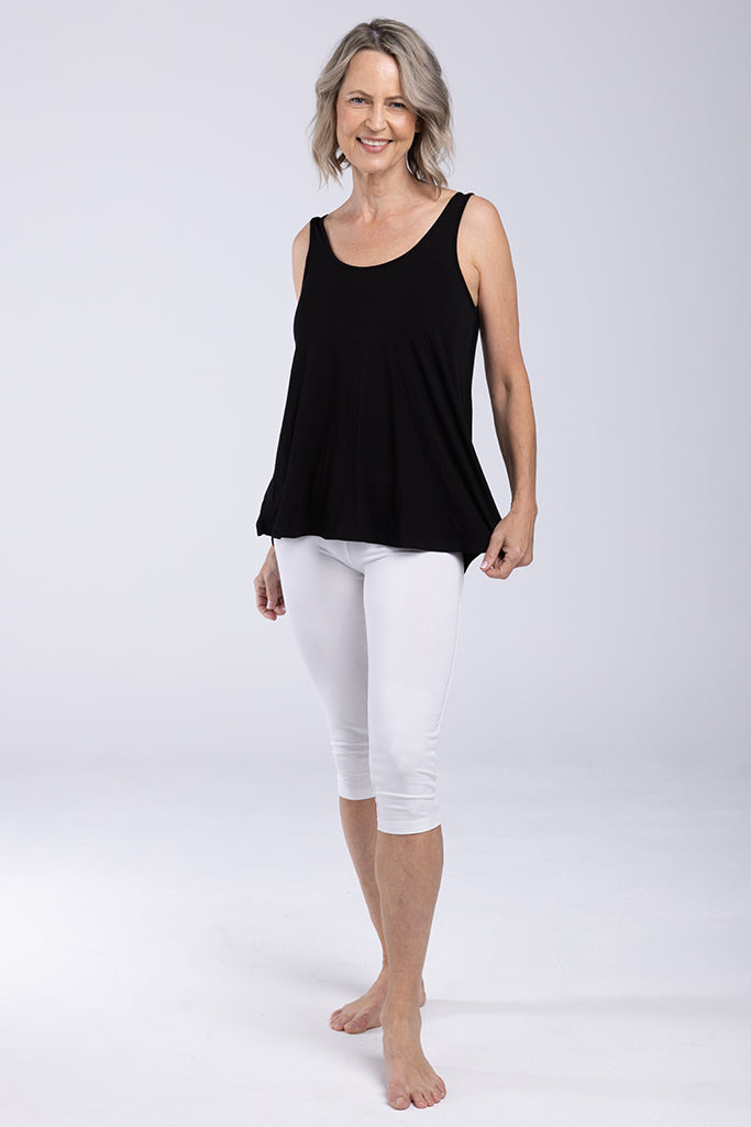 Front view of a model wearing a relaxed floaty singlet with a scoop neck line and white 3/4 leggings