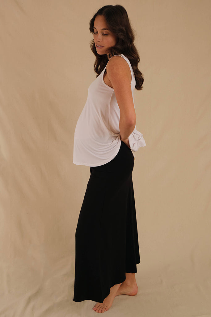 Pregnant model showing relaxed white singlet flowing softly over her pregnant belly providing good coverage.