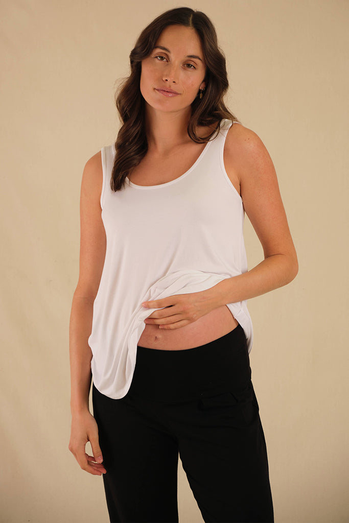 Pregnant model wearing relaxed white maternity singlet made of super soft and breathable bamboo fabric perfect for pregnancy and postpartum.
