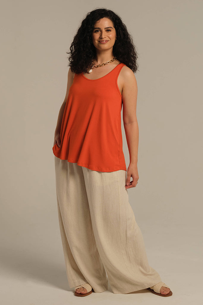 Standing model wearing a-line shaped orange singlet paired with wide leg pants for a floaty breezy summer look.