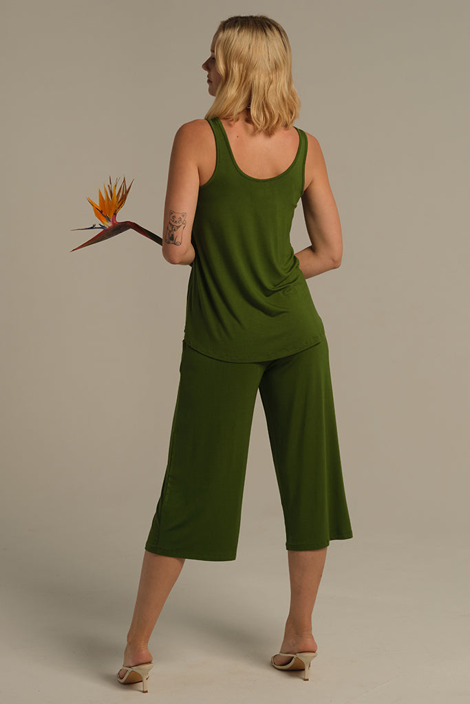 Back view of standing model in a green relaxed singlet with scoop neckline and green pants