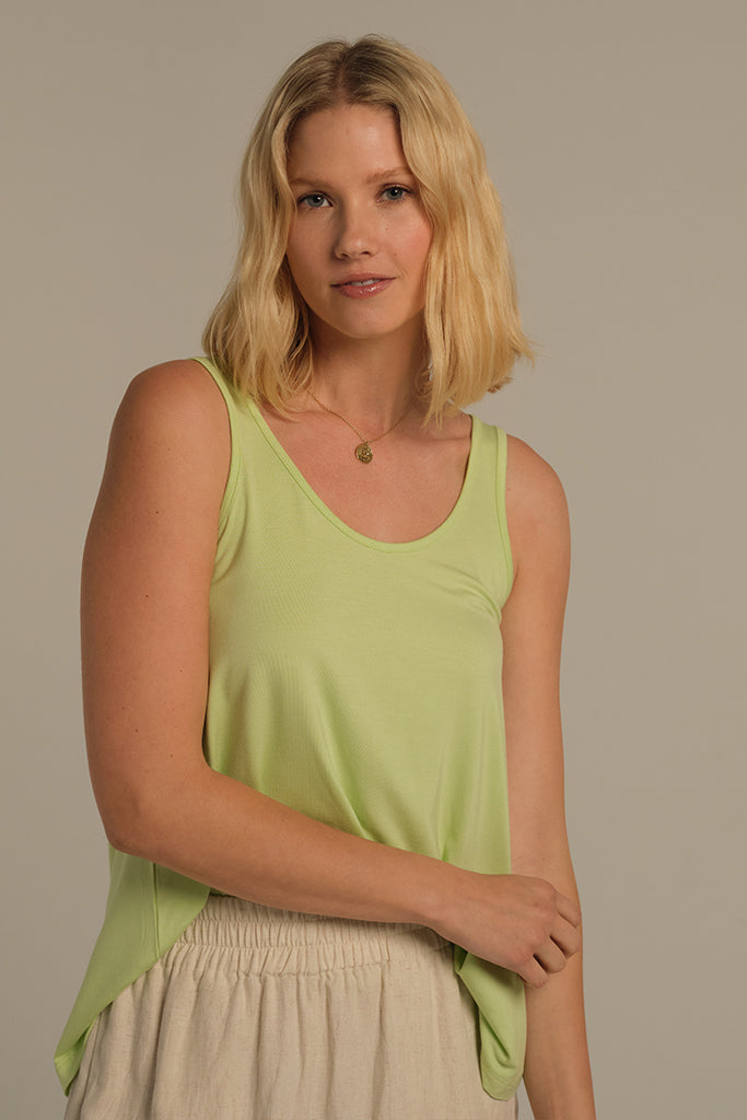 Model is wearing a pale green singlet with scoop neck tucked into her pants