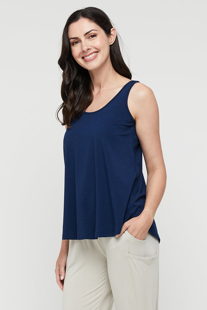 Model standing wearing navy relaxed bamboo singlet with light coloured pants