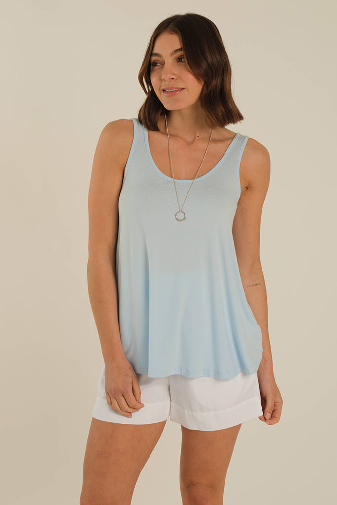 Model is wearing a baby blue hip length soft bamboo singlet paired with white shorts.