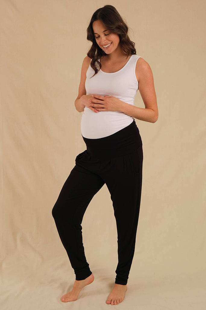 a pregnant woman wearing comfy bamboo slouch pants with wide and soft waistband and cuffed ankles