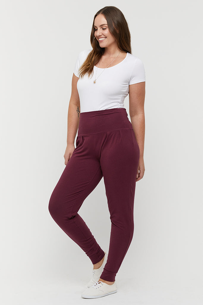 a model wearing burgundy slouch pants wit cuffs at the ankles and a wide soft waistband