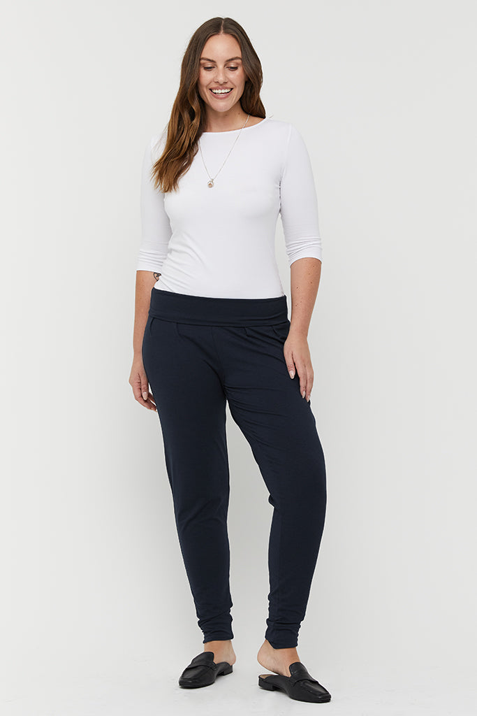 a model wearing dark navy bamboo slouch pants with a foldable soft waistband and cuffed ankles