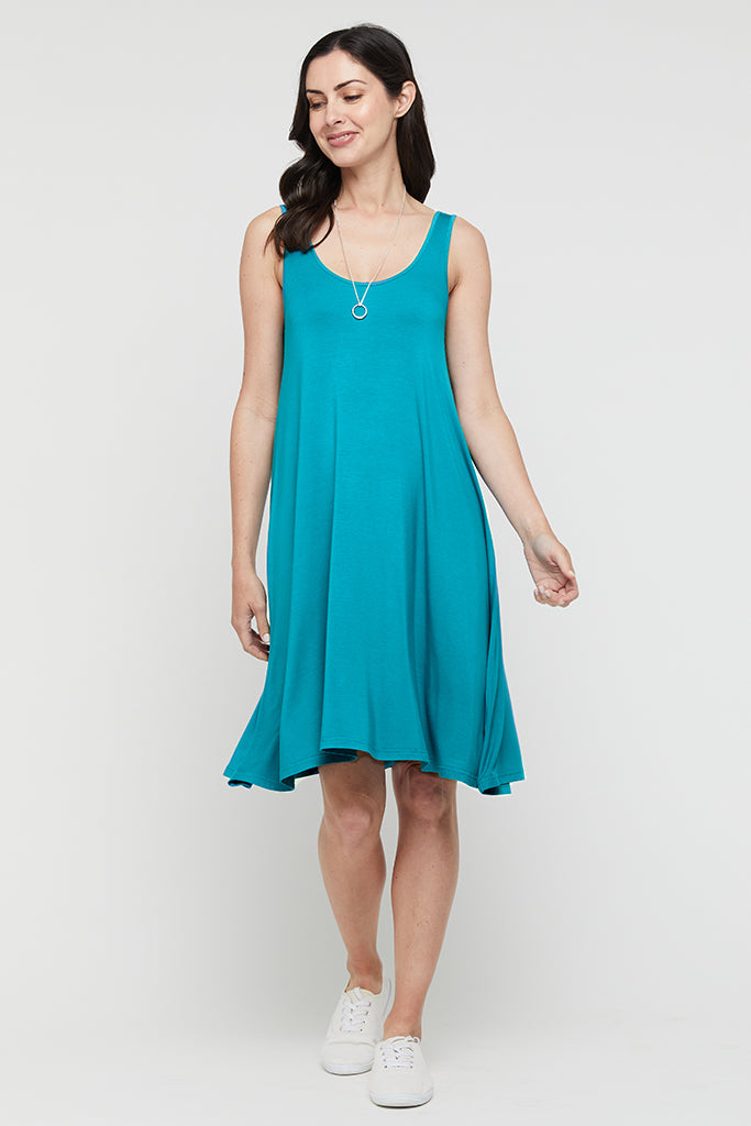 Model wearing a knee length teal dress paired with white sneakers