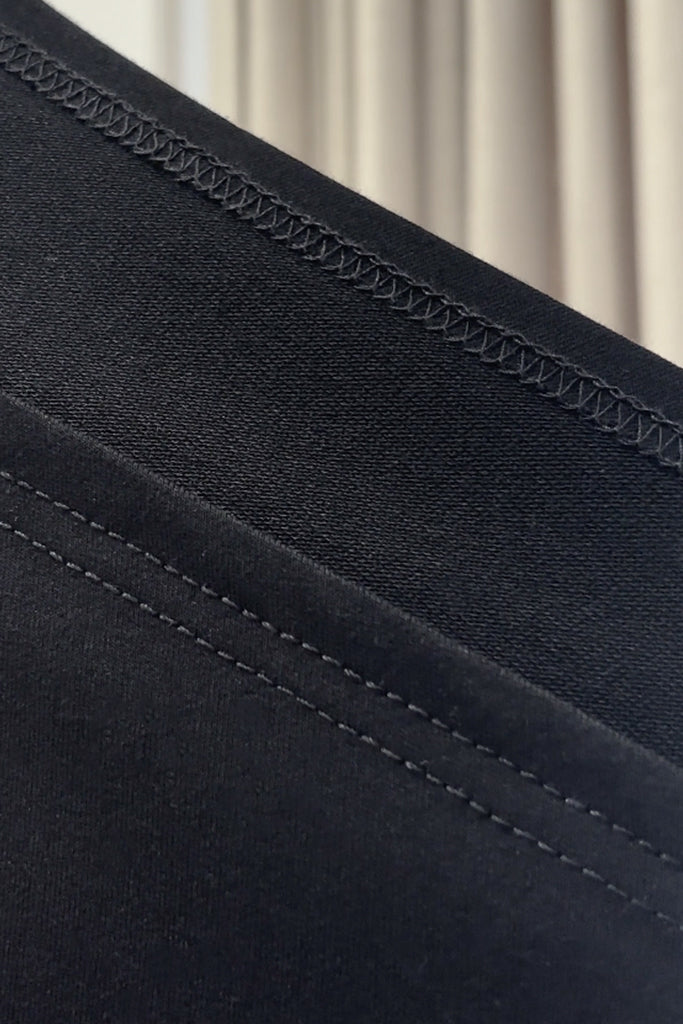 Close-up of black bamboo french terry fabric with stitching detail against a neutral background