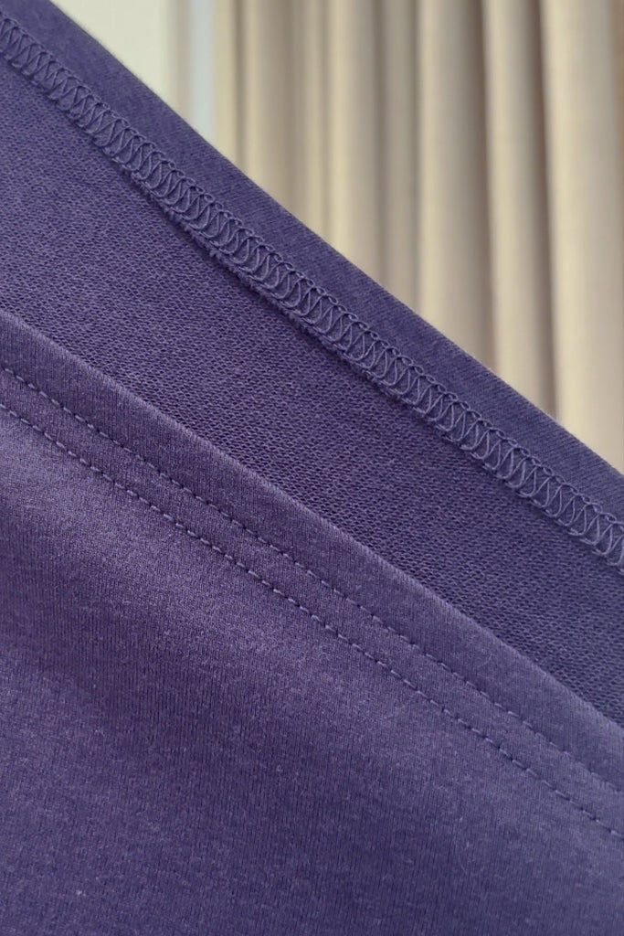 Close-up of purple bamboo french terry fabric with stitching detail against a neutral background