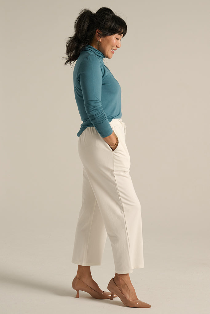 side view of the white straight pants paired with the teal turtleneck top