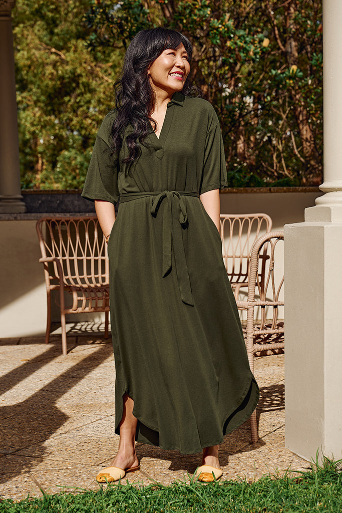 Woman wearing a green maxi dress standing outdoors with trees in the background