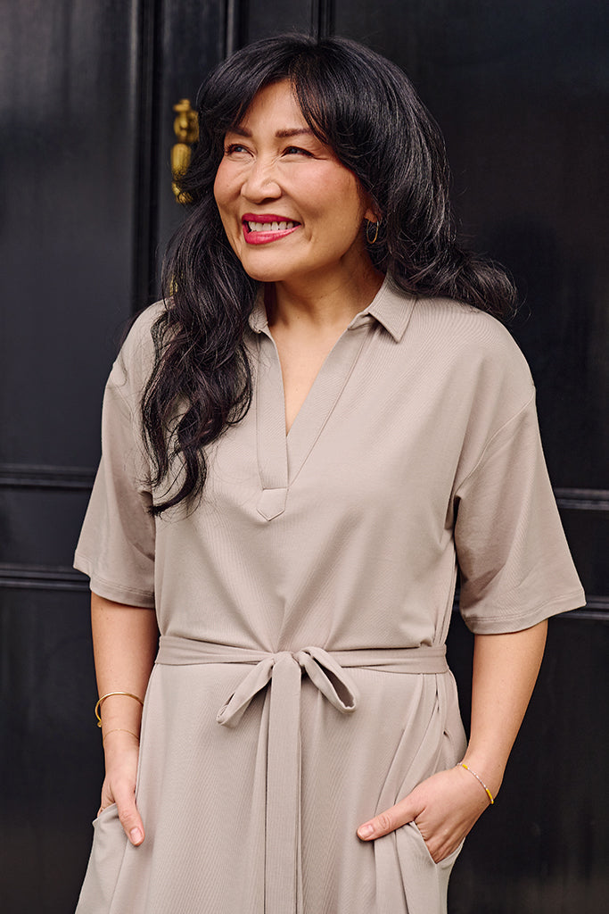 Close up of model wearing a taupe dress with a tie around the waist.
