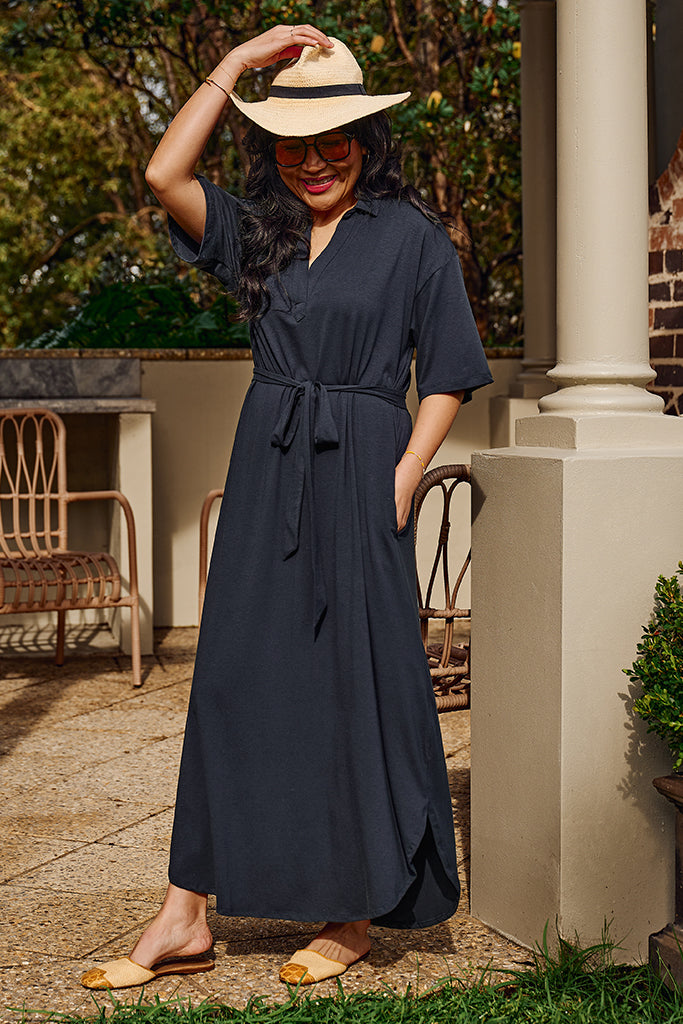 Model wearing a bamboo-linen maxi dress in washed navy, featuring side pockets, v neckline and above elbow sleeves