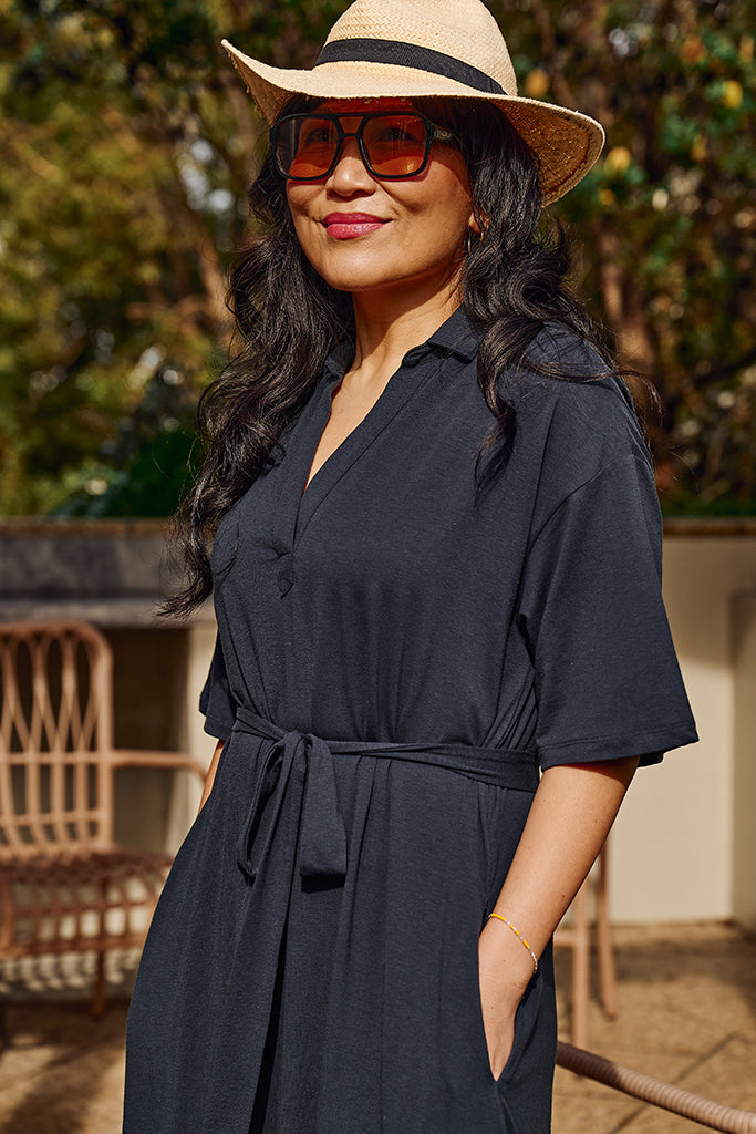 Close up of washed navy bamboo-linen maxi dress, paired with sunglasses and a beige hat.